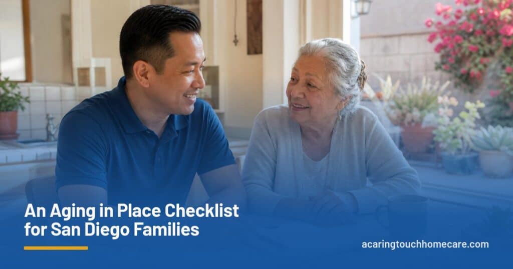 A caregiver and an older woman chat over a notepad at a sunny San Diego kitchen table.