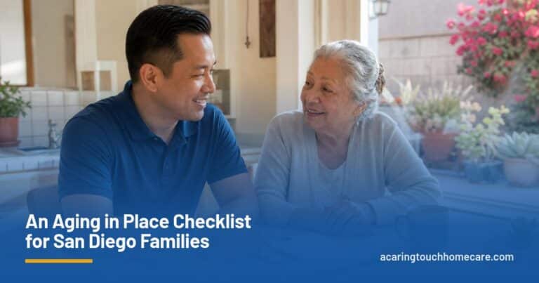 A caregiver and an older woman chat over a notepad at a sunny San Diego kitchen table.