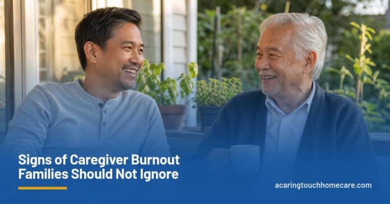 An adult son and his elderly father share tea and a laugh on a sunny back porch.